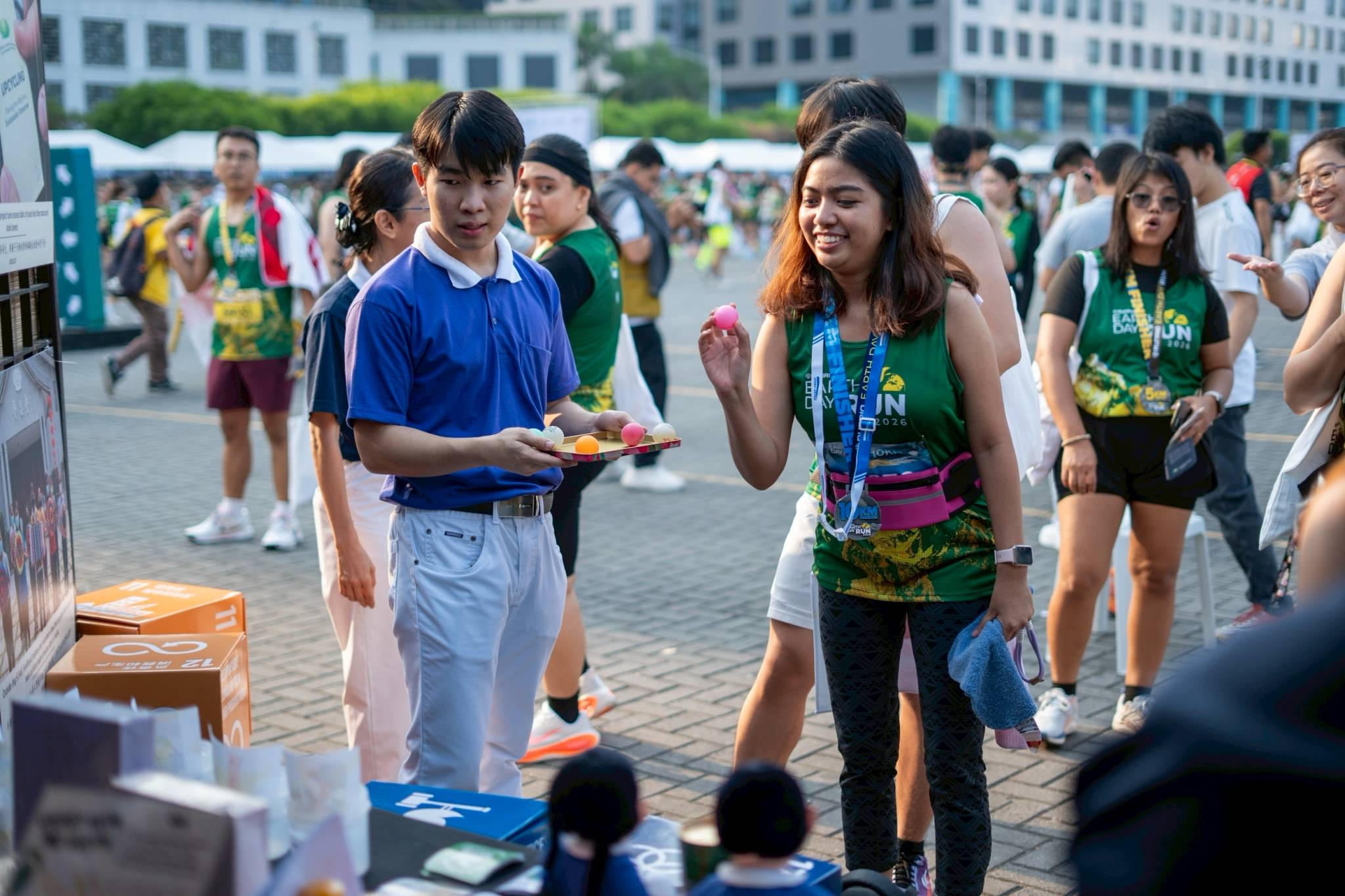 At the Tzu Chi Foundation booth, runners take turns shooting ping-pong balls into cups with drawings of the “essentials” and “threats” to planting a mangrove seedling. The object of the game is to shoot balls into cups with “essentials.” 