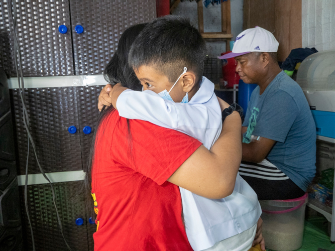 Venus Telecio (in red) receives a genuine hug from her youngest son, Vince Angelo, while preparing for school.