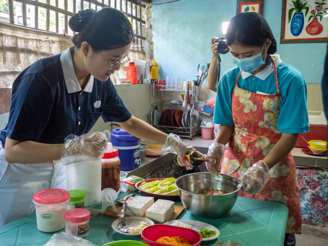 Tzu Chi volunteer Kelly Guo (left) helps Mikaela Tuazon pour the soy sauce to have a perfect blend for Vegan Shanghai.