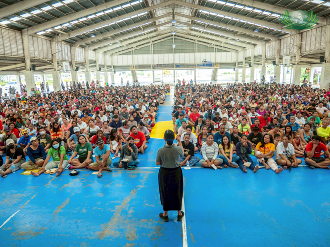 Tzu Chi volunteer Julie Collado addresses beneficiaries at the Sisters of Mary Girlstown covered court in Talisay, Cebu. 