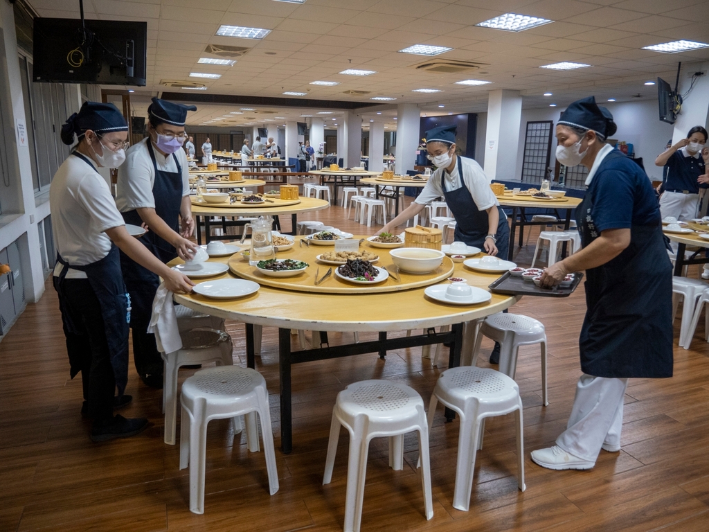 Tzu Chi staff and a Tzu Chi volunteer work together in setting the tables before mealtime.