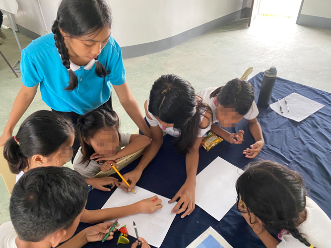 A scholar guides the children in a drawing activity.