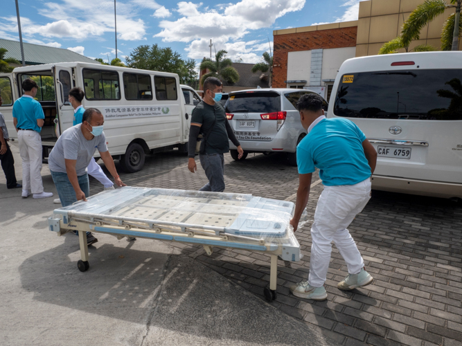 Tzu Chi staff members and scholars work together to transport a hospital bed, which will serve the institution's future clinic.