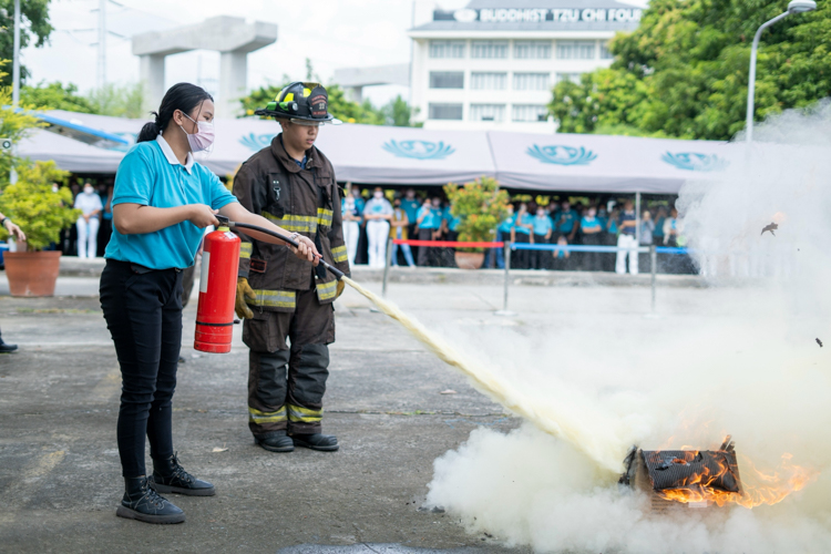 A scholar puts out controlled flames with a fire extinguisher. 