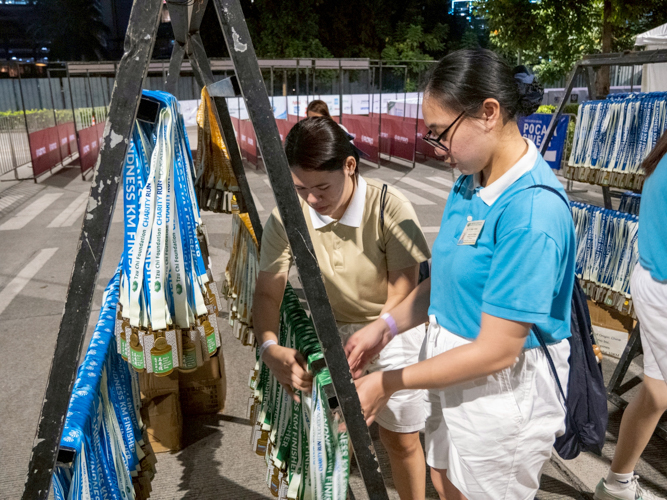 Tzu Chi academic and tech-voc scholars arrange the coin-can–inspired medals for distribution at the finish line.