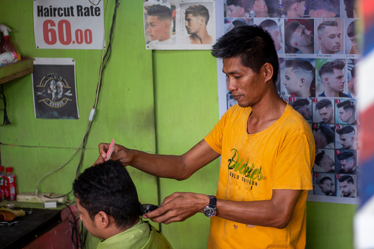 Prosthesis recipient Joey Bolandrina (right) skillfully trims a customer’s hair.