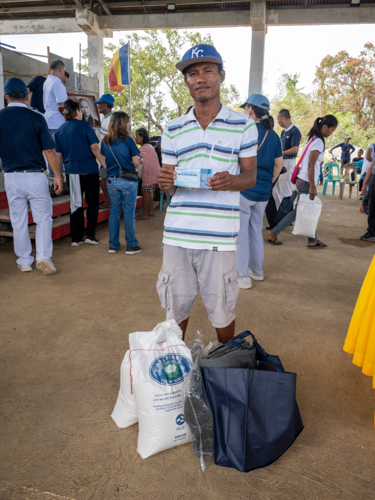 Fisherman Ray PJ Aliguia smiles, grateful for the essential goods and voucher for construction materials that will help his family recover from the typhoons. 