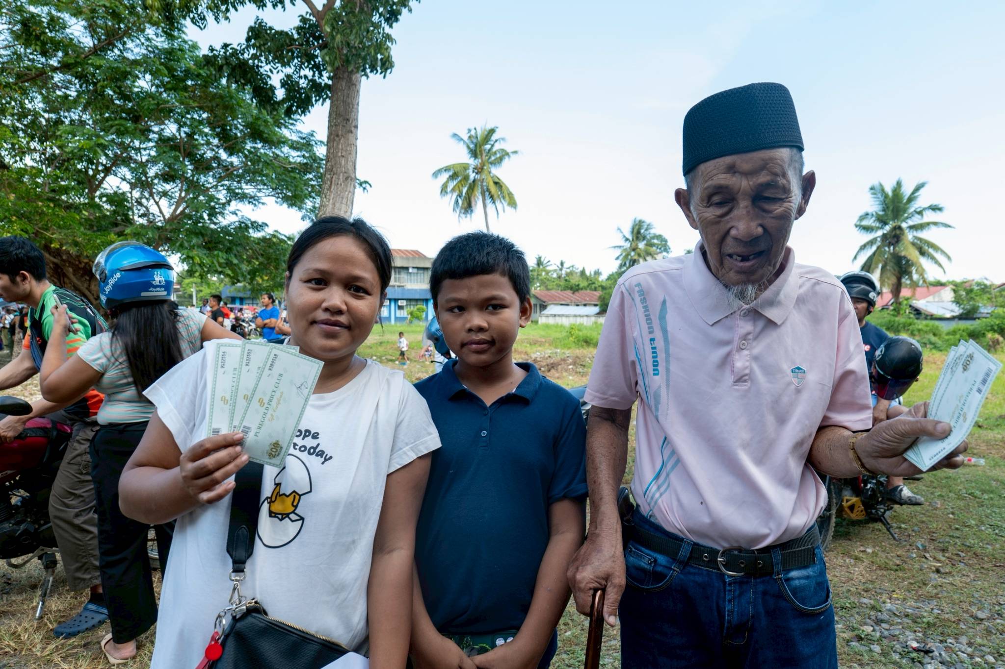 Tadni Acampong (right) and his family hold up the grocery gift checks they received from Tzu Chi. 