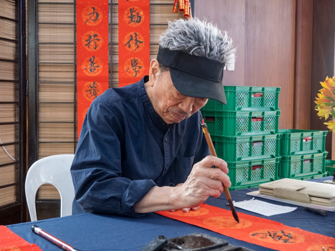 Chinese calligraphers stationed by the entrance of Jing Si Auditorium hand-write auspicious messages in scrolls for guests to hang in their homes. 