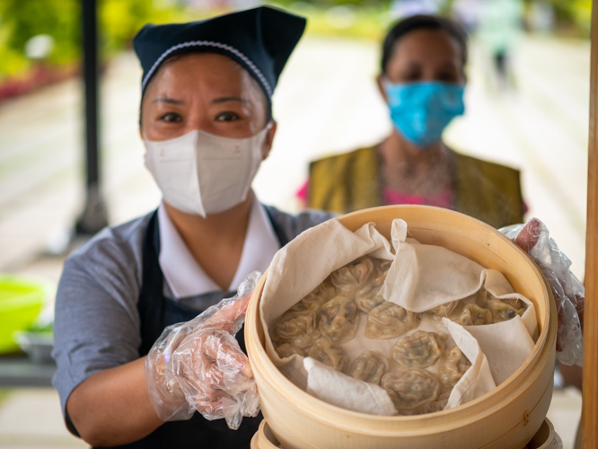 A volunteer holds up steamed dumplings filled with corn, mushroom, and other meat-free ingredients. 【Photo by Daniel Lazar】