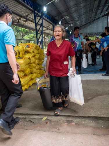 Beneficiaries are all smiles as they leave the distribution area with Tzu Chi’s relief goods. 