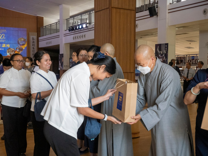 Dharma Master De Pei hands out the anniversary souvenir to Tzu Chi staff.