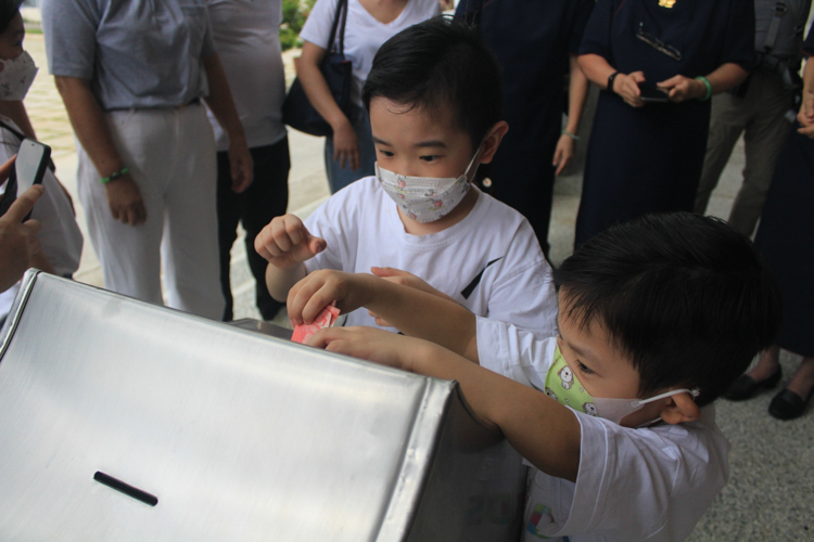 Children drop their pledges in a metal collection box. 【Photo by Kinlom】