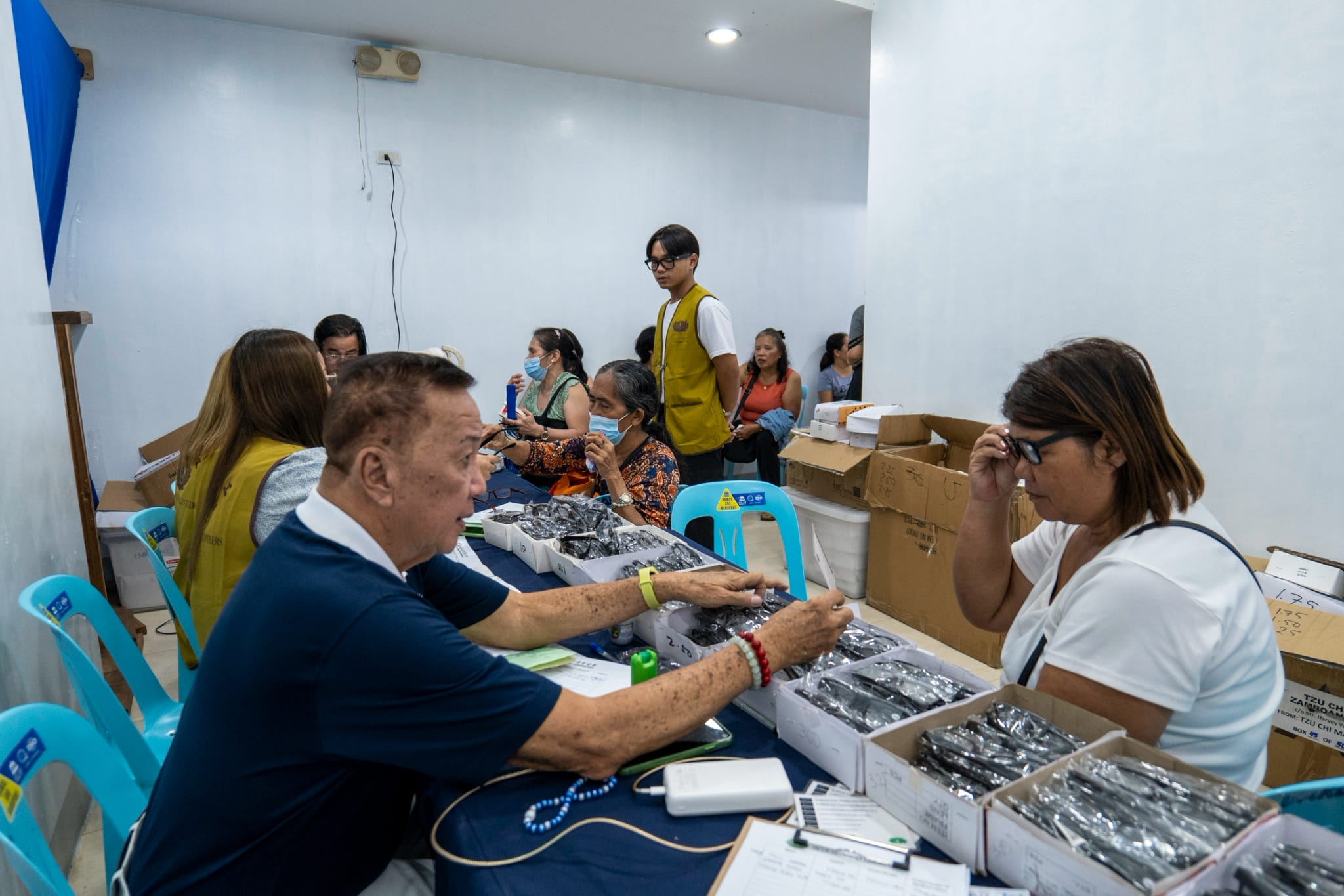 Beneficiary Marilou Jarlego receives free reading glasses. 