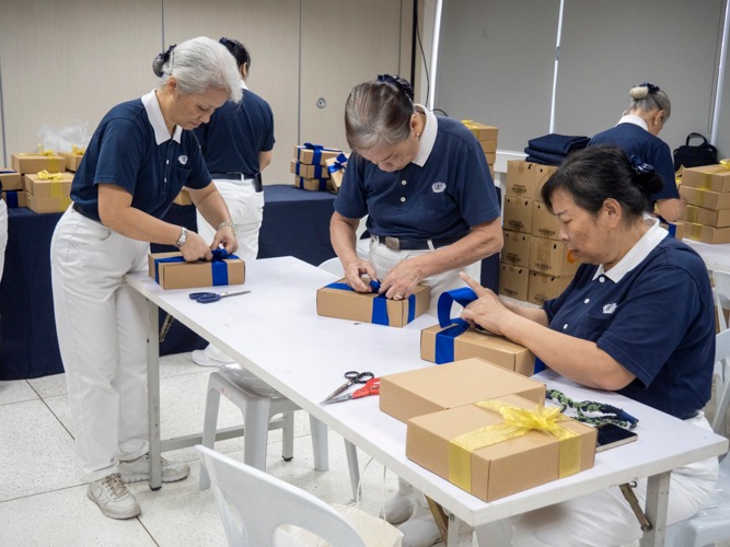 Tzu Chi volunteers tie ribbons on the lightbox package to be distributed as a souvenir.