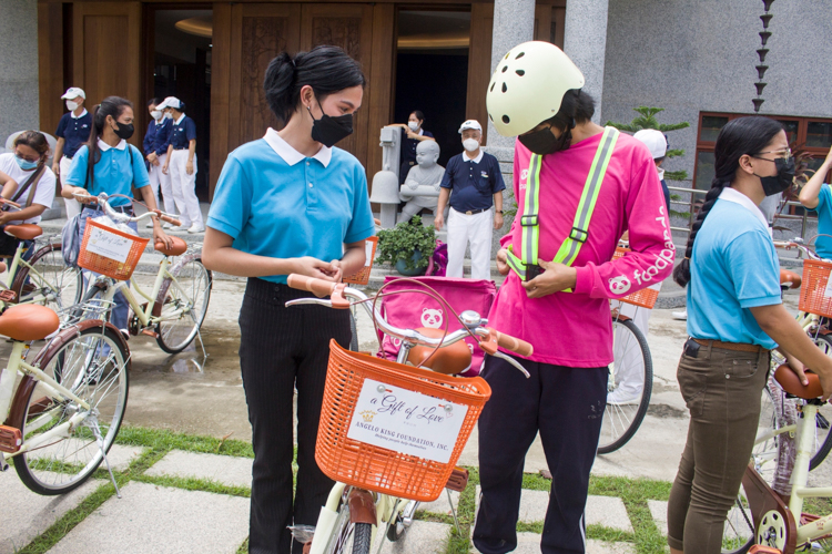 Tzu Chi scholar Jhasmine Yecla (left) looks on as her brother, Food Panda rider Justine Yecla, straps on the reflective safety vest that came with the bike. 【Photo by Matt Serrano】