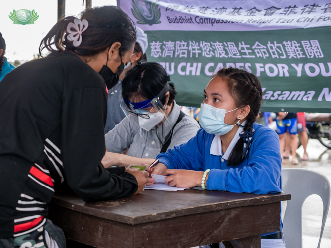 A Tzu Chi scholar assists a beneficiary in claiming her relief card. 