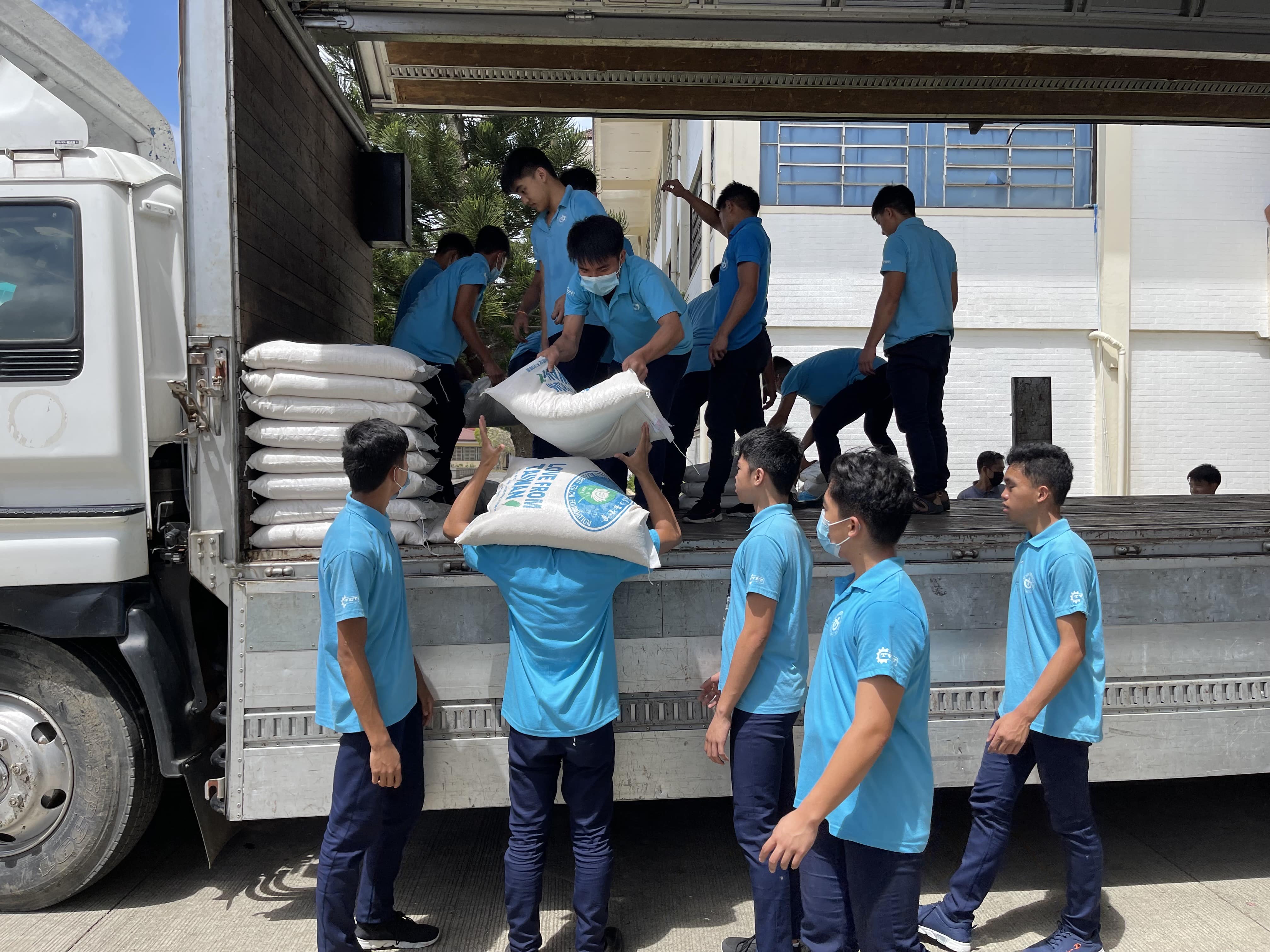 Boystown students help unload rice from the Tzu Chi Foundation truck.【Photo by Matt Serrano】