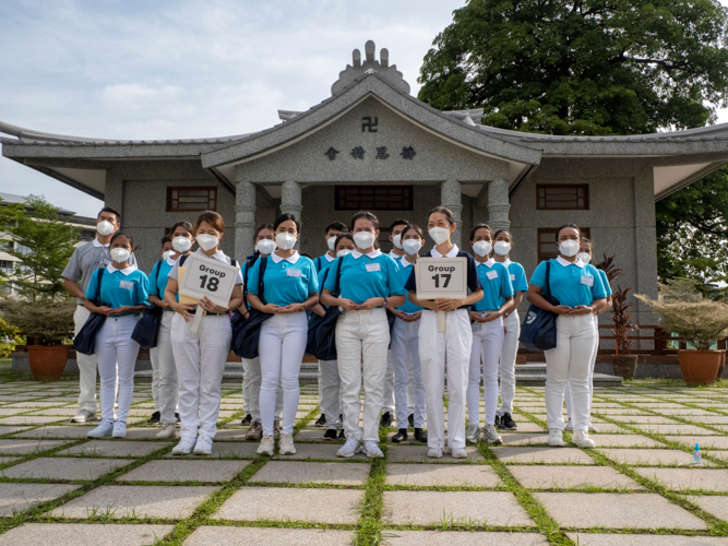 Scholars and their group leader pose outside a replica of the Jing Si Abode.【Photo by Matt Serrano】
