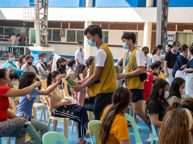 Ateneo de Davao University’s varsity basketball players help collect pledges from medical mission beneficiaries. The amount will fund future medical missions and other Tzu Chi programs for the poor. 【Photo by Matt Serrano】