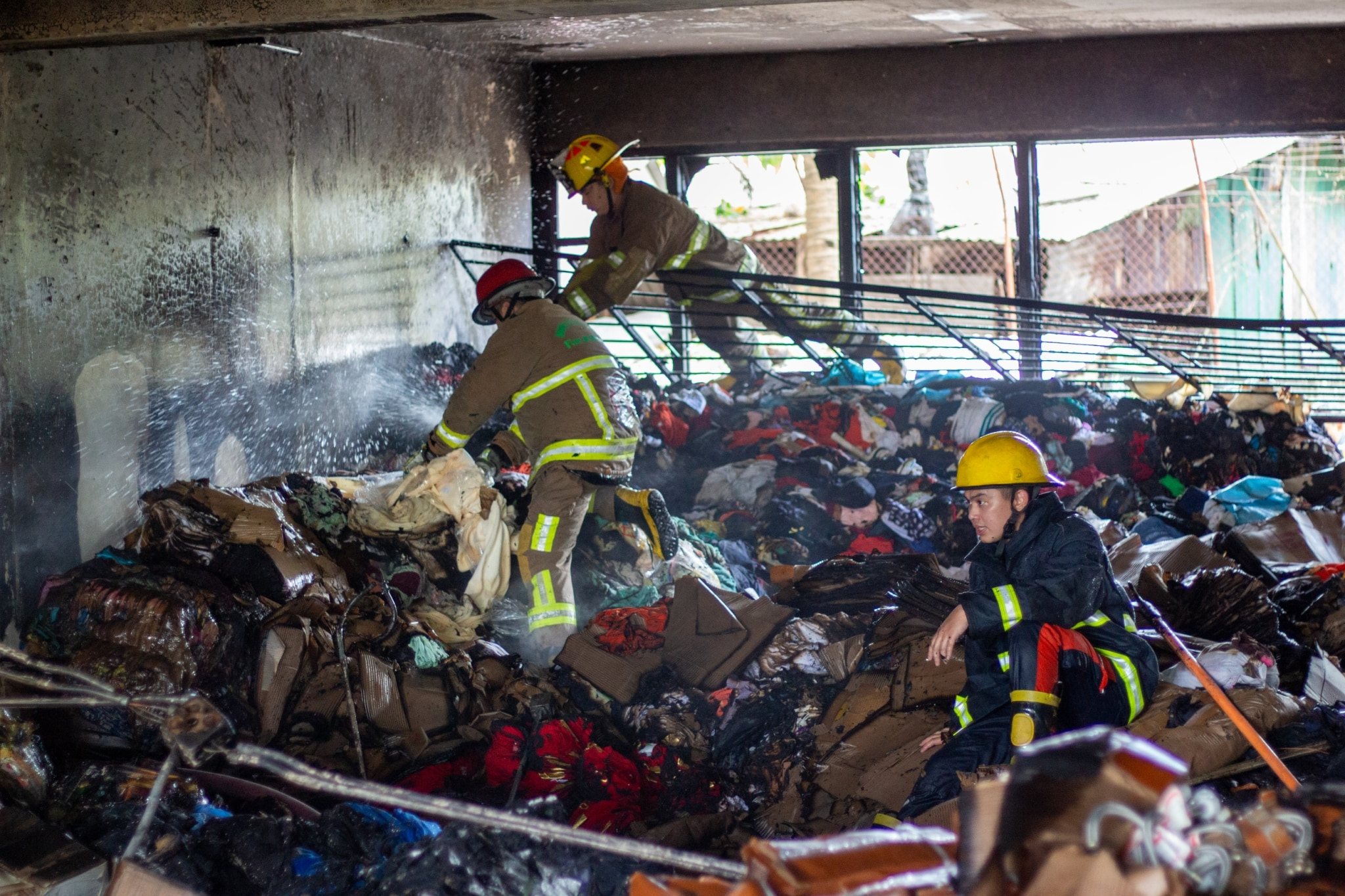 Firefighters inspect one of the burned out rooms. 【Photo by Harold Alzaga】