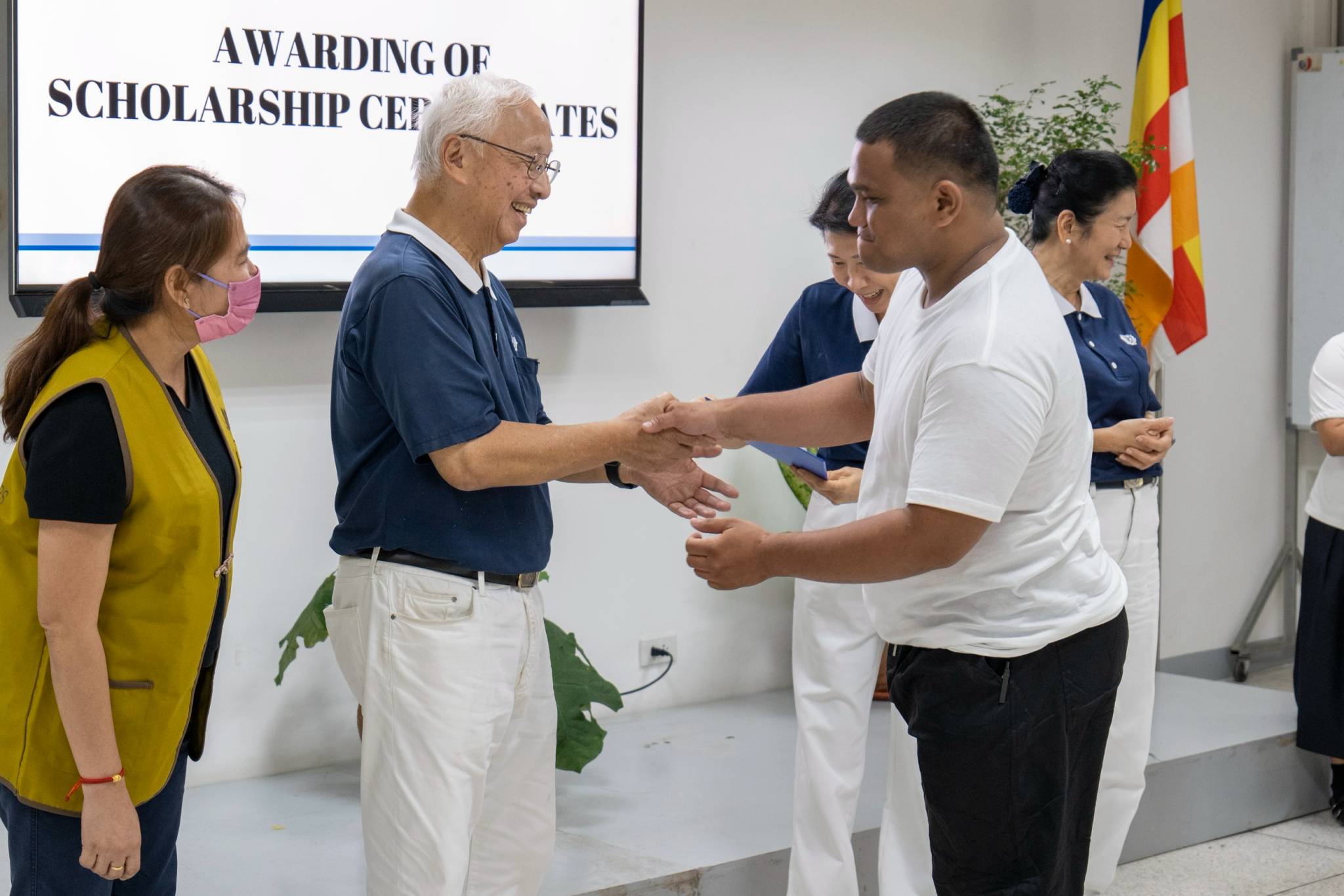 A moment of shared joy: Tech-Voc scholars exchange warm smiles with Tzu Chi volunteers as they proudly accept their scholarship certificates.