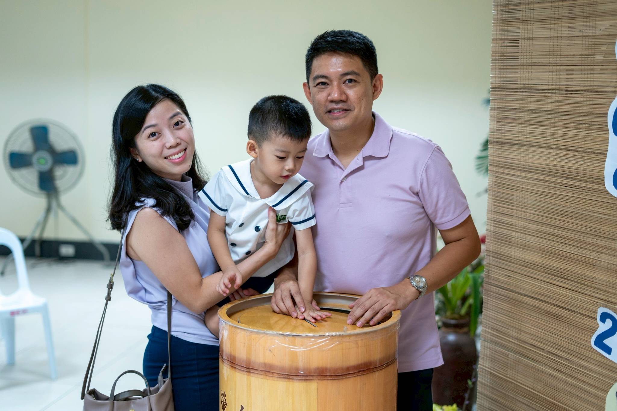 Parents Aaron and Mary Rose Lee guide their son Audee in opening his coin can. At a young age, toddlers are taught that kindness in giving begins with small acts that grow into powerful help for others.