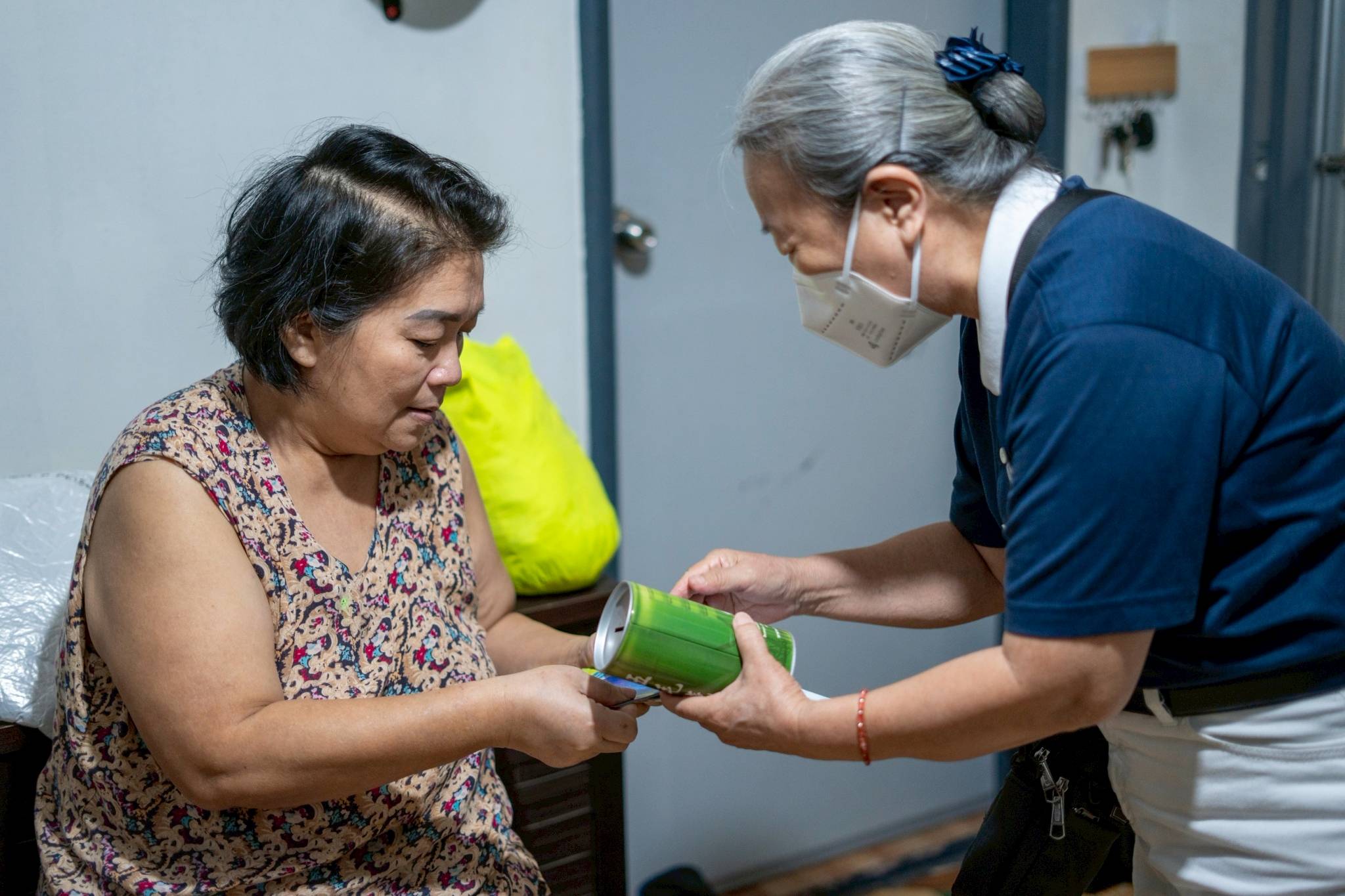 Pilar Ang Si receives a coin bank during a home visit from Tzu Chi volunteers. Through donations big and small placed in these cans, medical assistance beneficiaries like Pilar have the resources for timely treatment. 