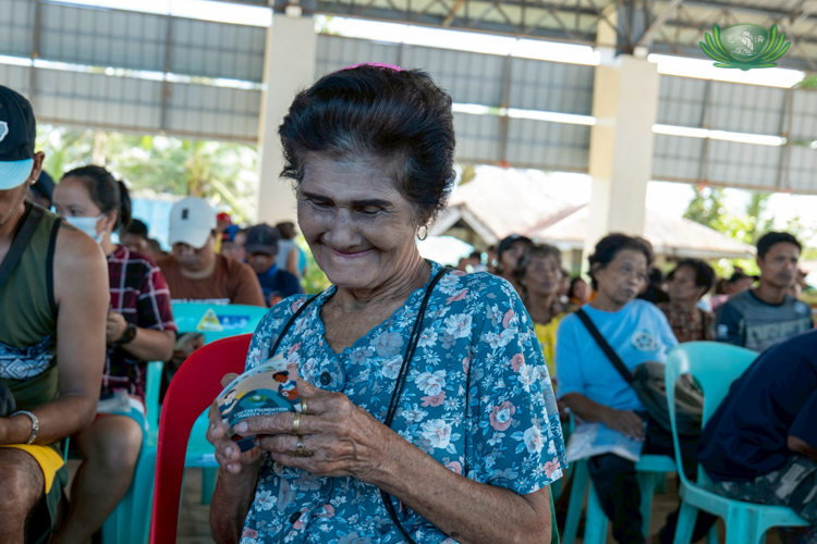 Angelina Candor, 76, resident of Barangay Ibona, flashes a hopeful smile as she waits for her name to be called at the registration table.