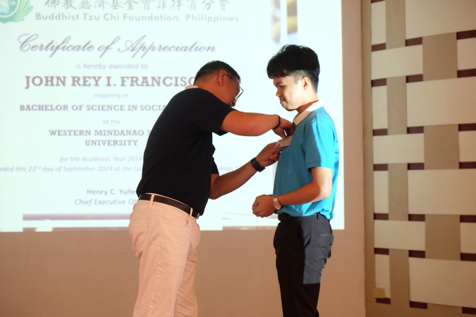 Tzu Chi Zamboanga OIC and Deputy CEO Dr. Anton Mari Lim (Left) pins a Tzu Chi ID on John Rey Francisco. 