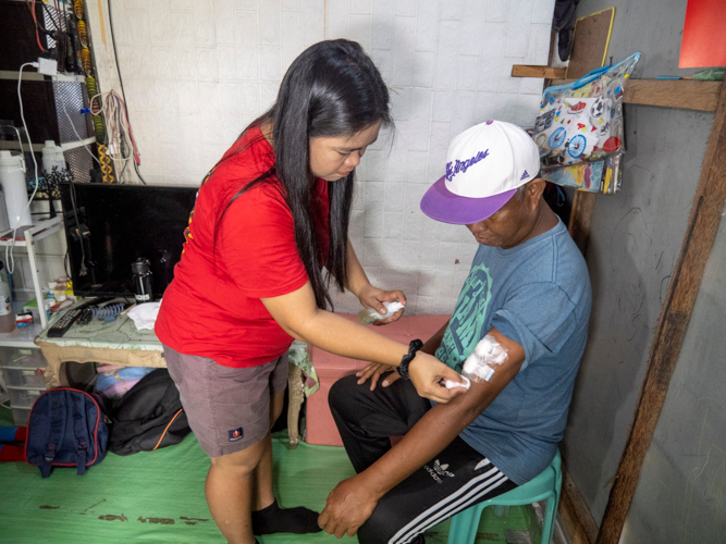 Caregiver at home: Venus Telecio (left) carefully cleans the injection sites of her husband, Levy, after his hemodialysis session.