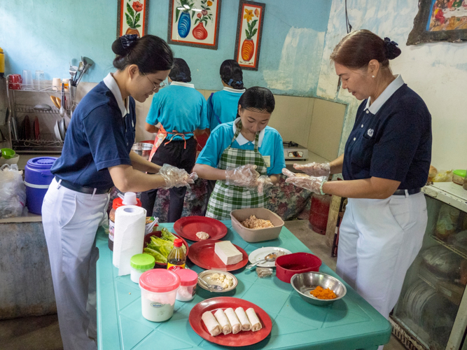 Tzu Chi volunteers help Kaye Sabornido (in checkered apron) form Tofu Nuggets from the ingredients mixed.