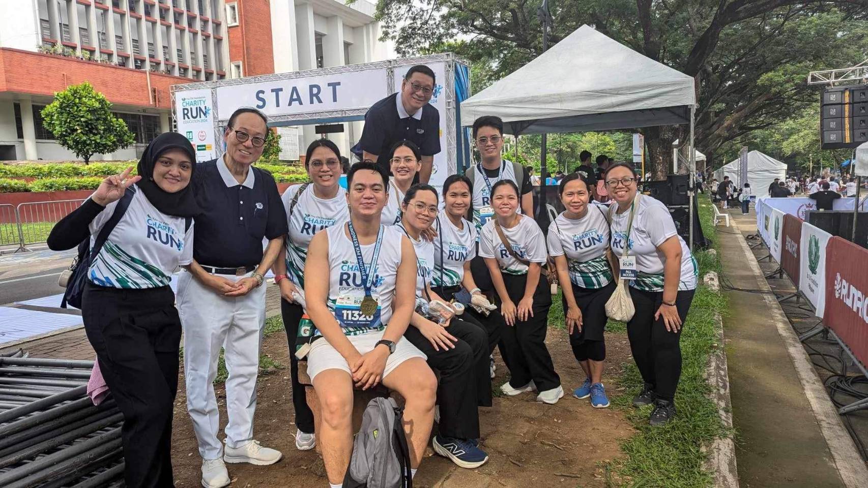 (Second row, second from right) All smiles with Tzu Chi Charity Department staff, Tzu Chi Bicol’s Tony Tan (standing, second from left), and Tzu Chi Zamboanga’s Dr. Anton Mari Lim (back row) after the Tzu Chi Charity Run for Education at the University of the Philippines, Diliman, in 2024