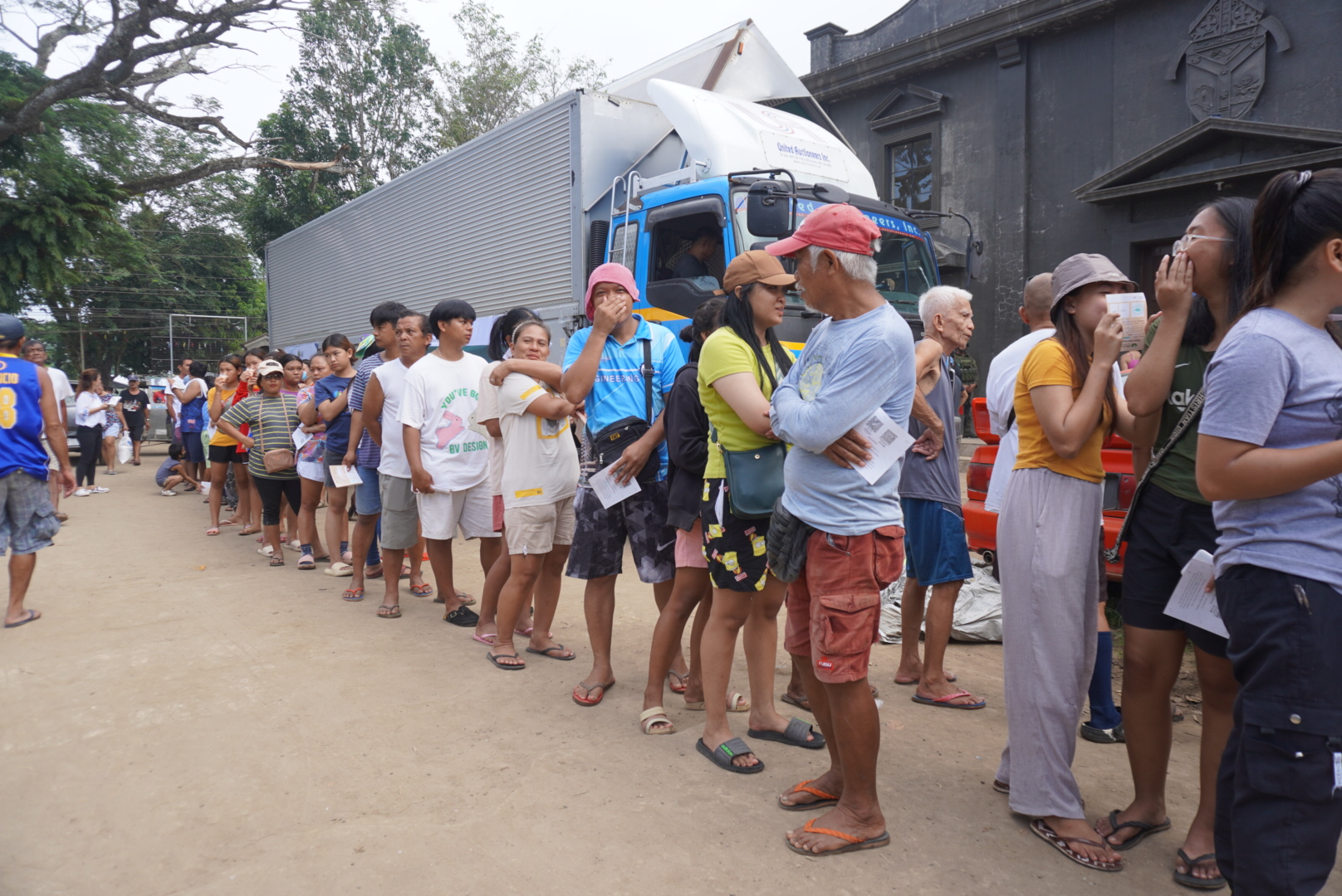 Survivors of Typhoon Kristine (Trami) line up outside a church in Barangay San Roque, Bula, Camarines Sur, to each claim a 10-kilo sack of rice from Tzu Chi volunteers. 