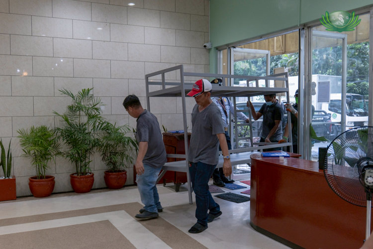 Tzu Chi staff members help carry the bunk beds to the QMMC hospital lobby.