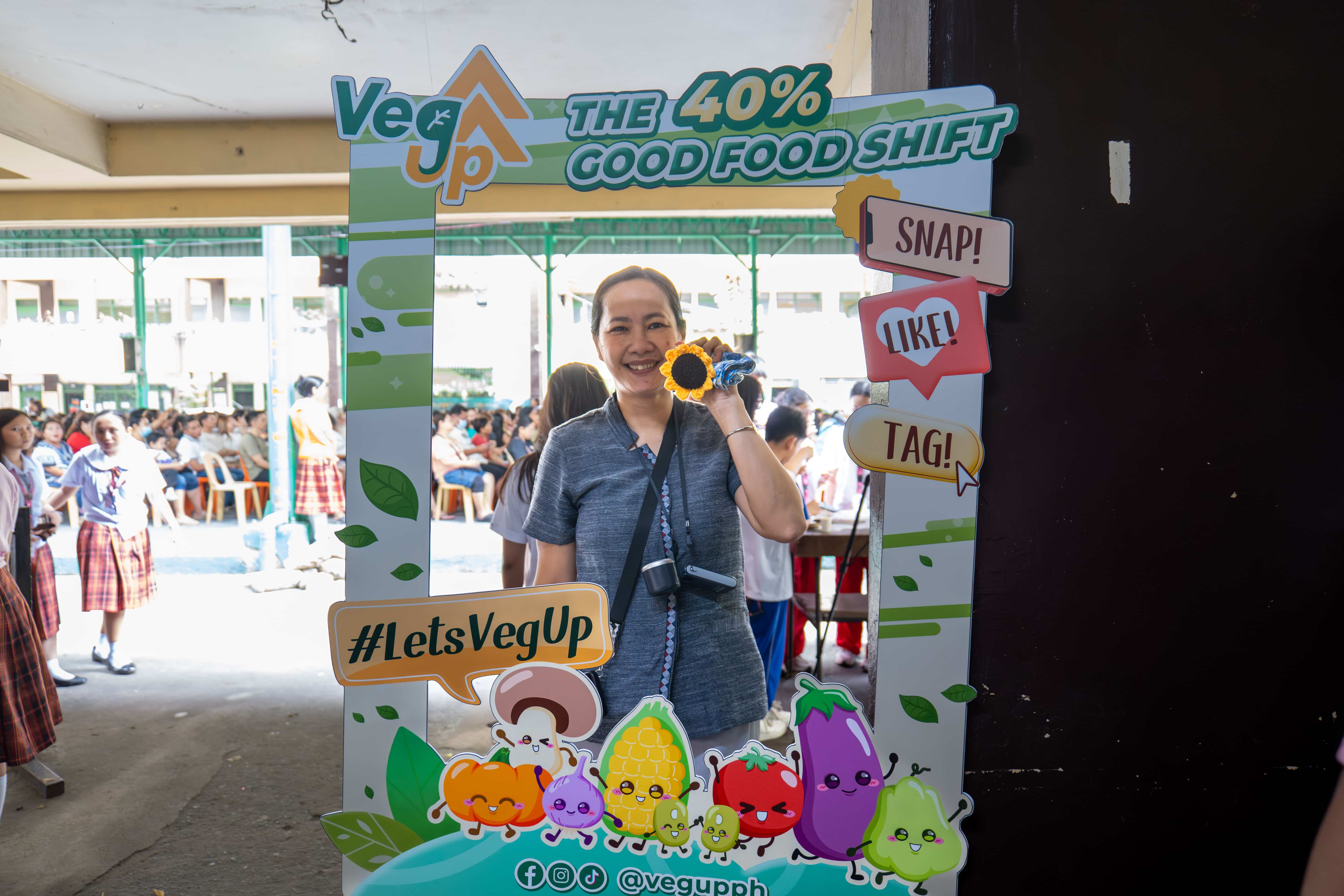 Faculty member Emily Q. Mesina poses at the photo booth with her sunflower plushie, a prize she won from the game.