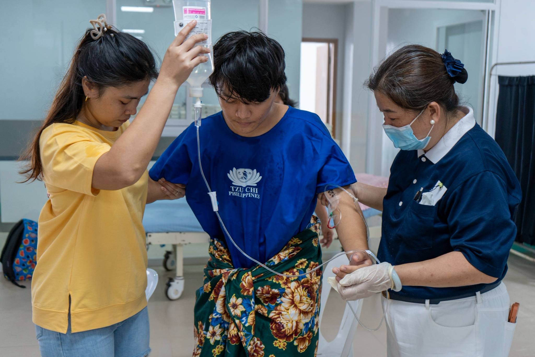 Laurence Sanchez (center) is assisted by his companion and a Tzu Chi volunteer after his hernia surgery. 