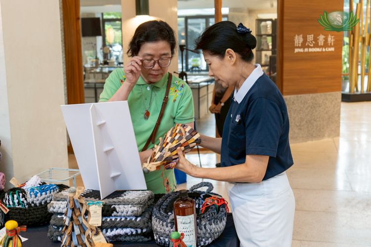 Tzu Chi Foundation Philippines Deputy CEO Woon Ng entertains a shopper interested in a Christmas tree made from strips of upcycled denim. 
