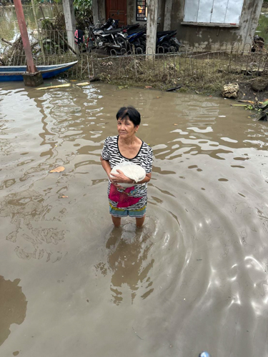 A resident wades in floodwater to claim a 5-kilo bag of rice.