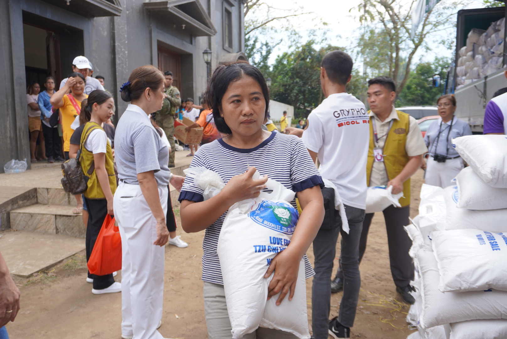 A woman carries a 10-kilo sack of rice she received from Tzu Chi volunteers during a distribution for survivors of Typhoon Kristine (Trami) organized outside a church in San Roque, Bula, Camarines Sur. 