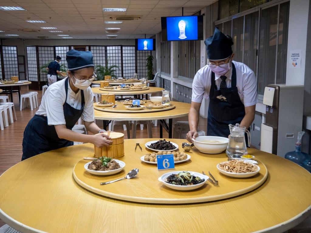 Joanne Prowel-Ang (left) works with fellow staff member Ian Manlulu (right) in setting tables.