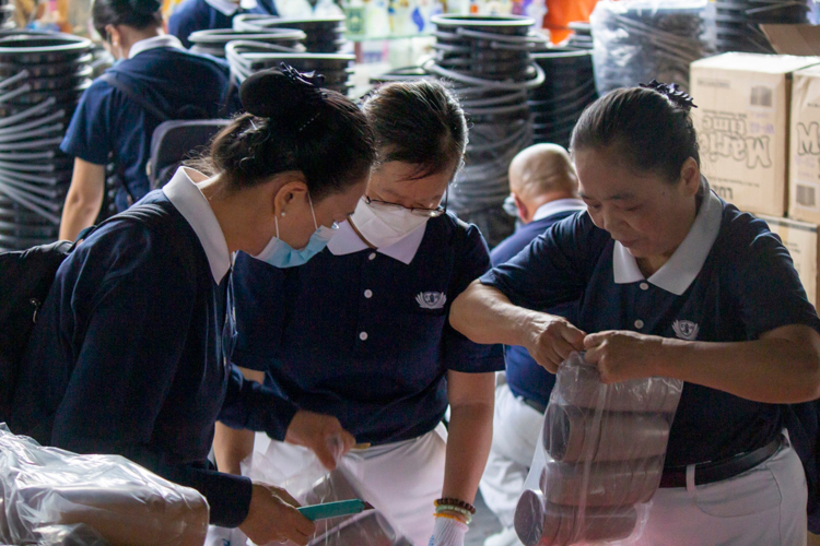 Tzu Chi volunteers help unpack the drinking cups for the relief distribution.