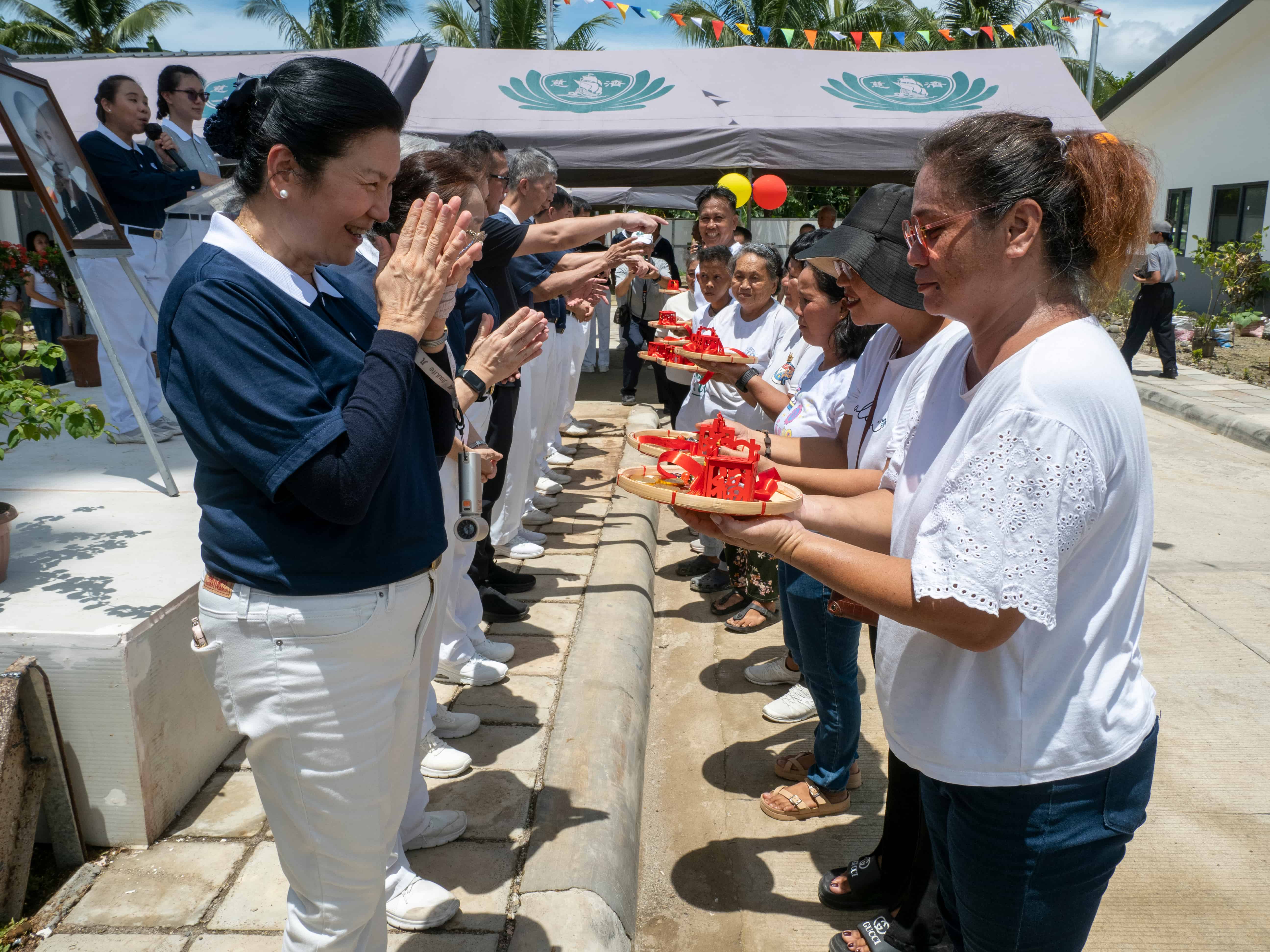 (Left) Cheering for a new homeowner during the turnover ceremony of permanent homes at the Tzu Chi Palo Great Love Village in Leyte in 2024.
