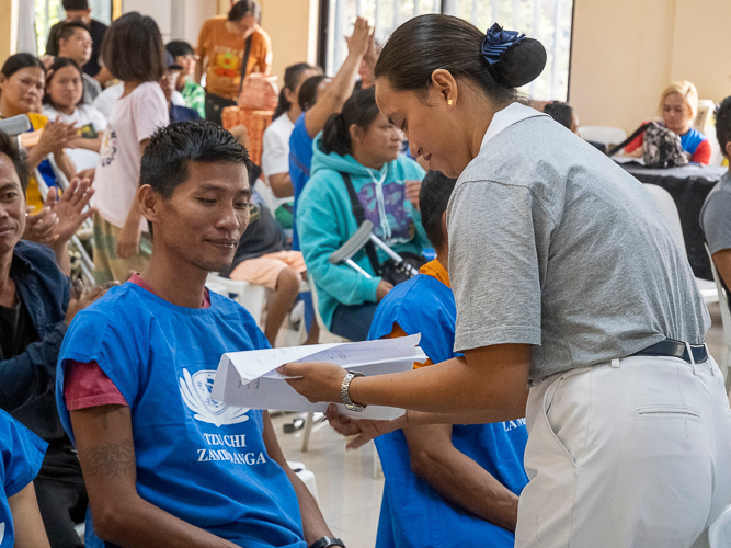 A Tzu Chi volunteer (right) assists Joey Bolandrina (left) with the registration before receiving his prosthesis.