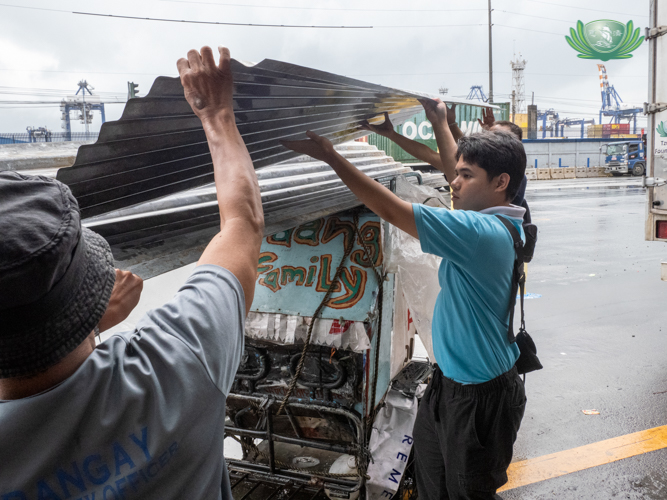 In Tondo, Manila, Tzu Chi scholar Karl Andrew Bonabon helps load GI sheets from Tzu Chi volunteers atop a tricycle.