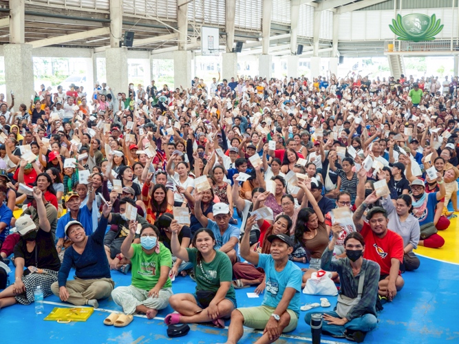 Beneficiaries wave their claim stubs.