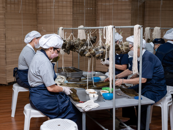 Volunteers hand-wrap the sticky rice in bamboo leaves and tie them securely with a string.【Photo by Daniel Lazar】