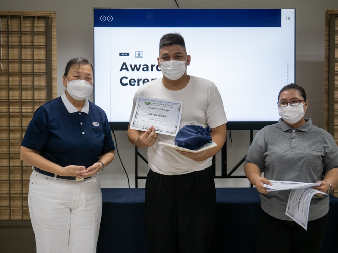 Tzu Chi caregiver scholar Kevin Malla (center) receives his certificate, caregiver uniform, and lunch kit from Tzu Chi Communications Department Head Judy Lao (left) and Tzu Chi Tech-Voc Department Administrator Elizabeth Auste (right). 【Photo by Jeaneal Dando】