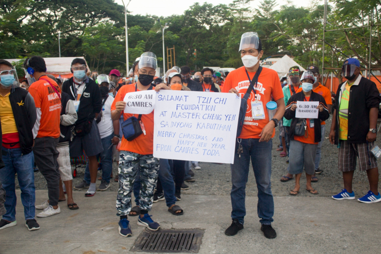 Tricycle drivers from CAMRES TODA show their thanks for Tzu Chi Foundation’s help with a sign. 【Photo by Matt Serrano】