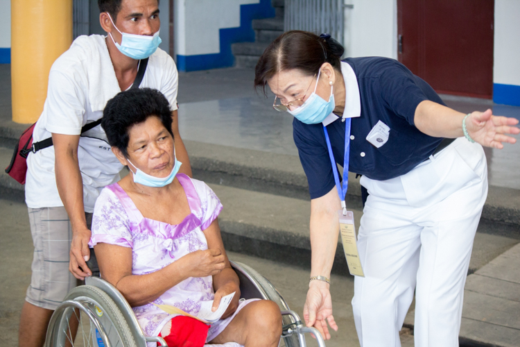 A volunteer guides Susana del Pilar to a doctor for a general checkup. Susana's right leg was amputated above the knee last June due to complications from diabetes. Now her left leg is giving her problems.【Photo by Marella Saldonido】